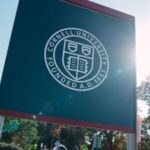 Close-up of the official dark green Cornell University sign featuring its white seal under clear ski