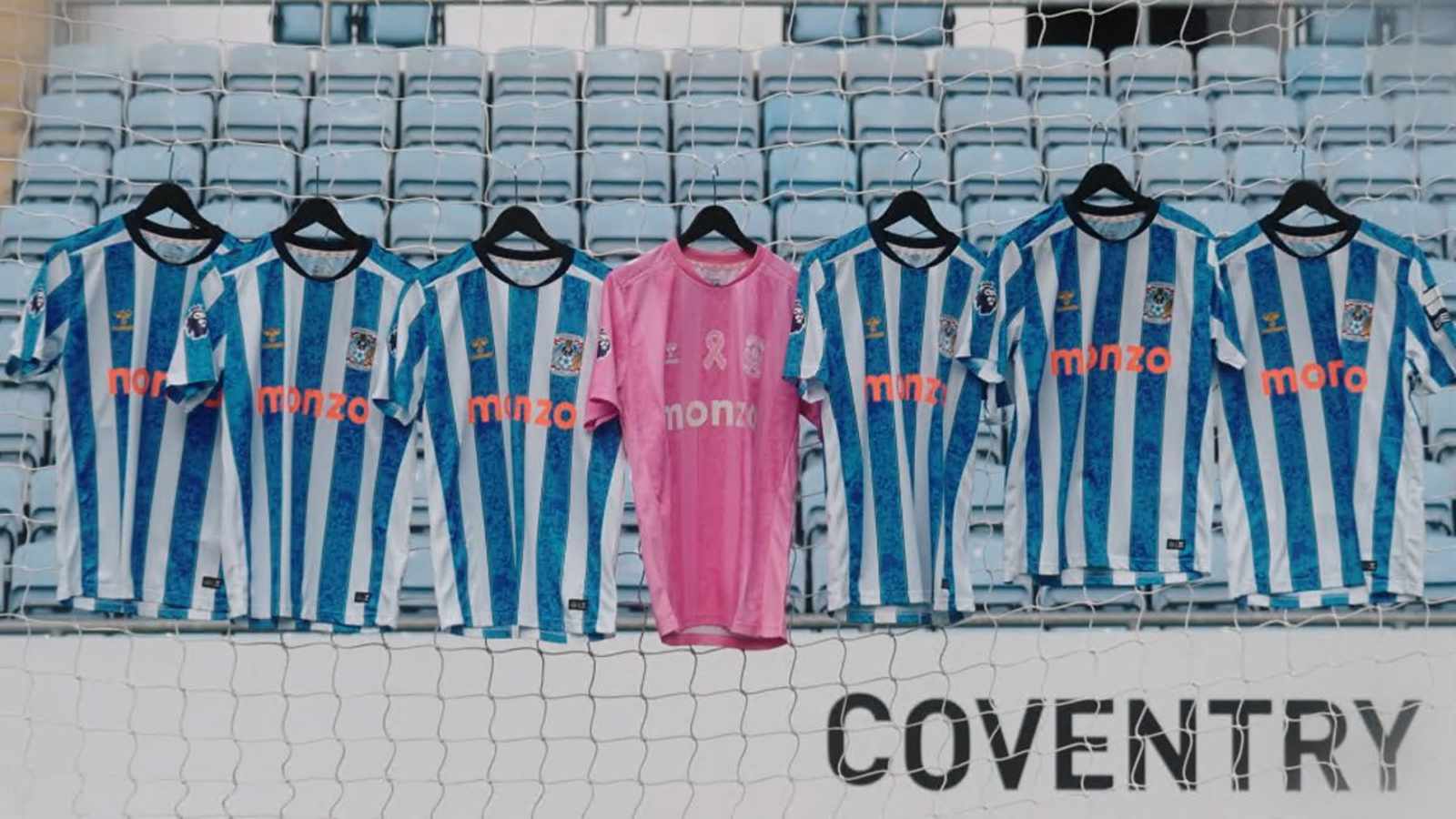 Coventry City football shirts hanging in front of stadium seats, featuring a special all-pink breast