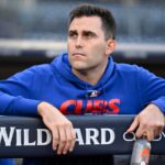 A Chicago Cubs player in a blue hoodie looks dejected in the dugout during a playoff game