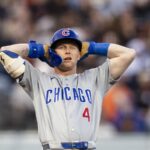 A Chicago Cubs baseball player with hands on his head looking frustrated on the field