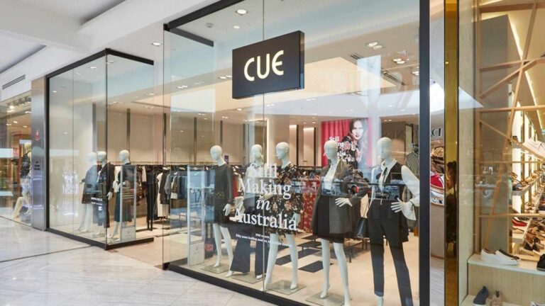 A Cue clothing boutique storefront displaying mannequins in a modern shopping center