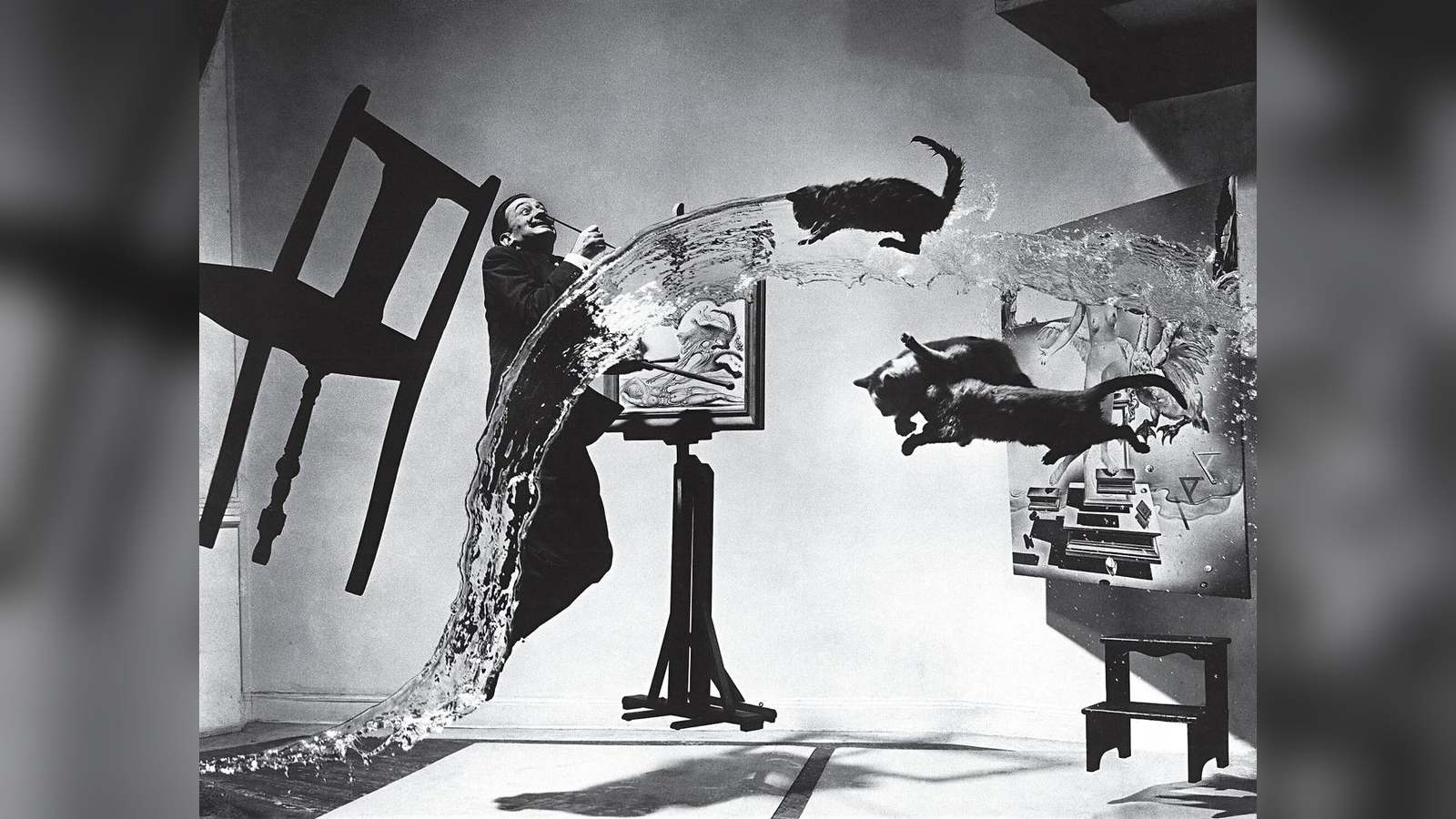 Salvador Dalí leaps mid-air alongside flying cats, thrown water, and suspended furniture in Philippe