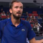 Daniil Medvedev wearing a blue polo shirt gesturing on a tennis court during a match