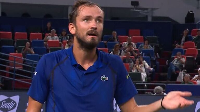 Daniil Medvedev wearing a blue polo shirt gesturing on a tennis court during a match