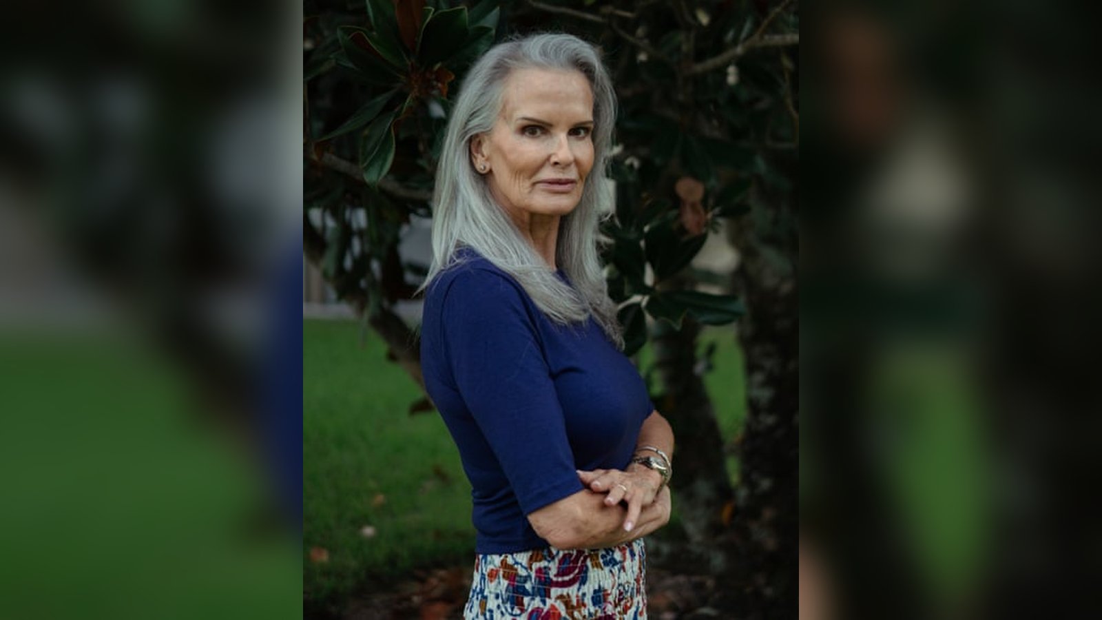 Denise Brown with long grey hair wearing a blue shirt outdoors