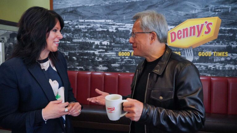 Dennys CEO Christopher Bode talking inside a diner restaurant holding a coffee mug