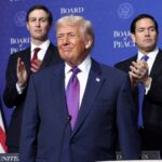 Donald Trump standing in front of American flags with Jared Kushner and Marco Rubio