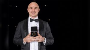 Dylan Edwards wearing a tuxedo and holding a medal in a presentation box