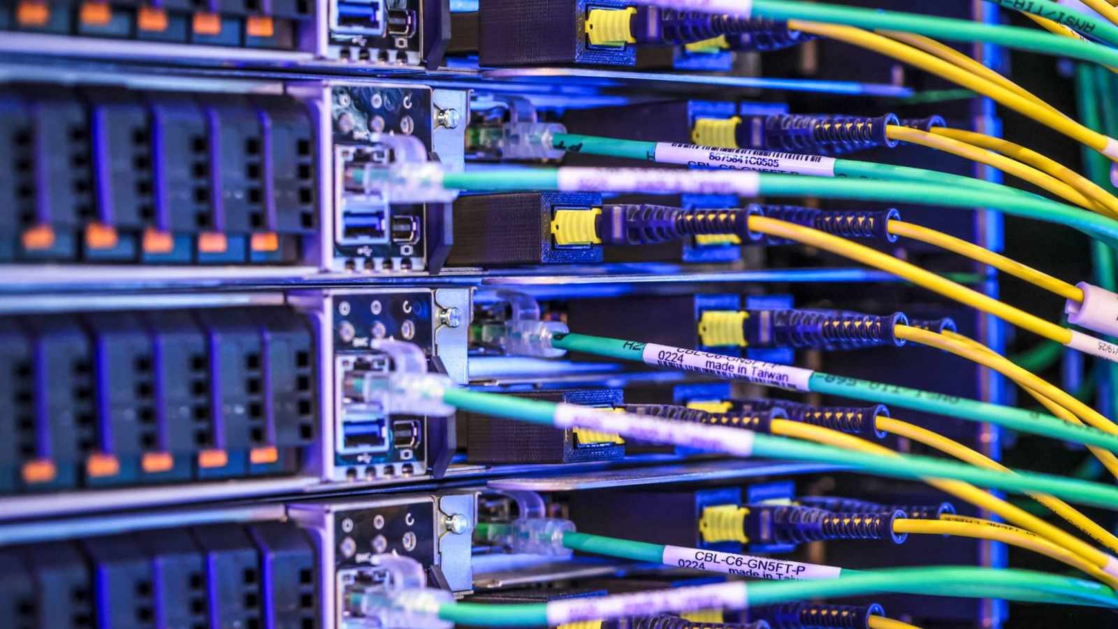 Close up of server racks and connected green and yellow network cables in a data center