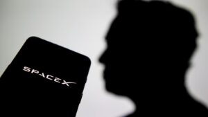 Silhouette profile of Elon Musk next to a smartphone displaying the SpaceX logo