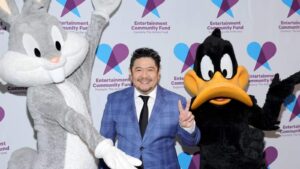 Voice actor Eric Bauza posing with Bugs Bunny and Daffy Duck mascots at an event