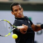 Felix Auger-Aliassime playing tennis on court during a match, hitting a forehand shot