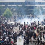 Large crowd of protesters gathering in a French city amid smoke and demonstrations