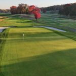 Aerial view of a pristine golf green surrounded by bunkers and autumn foliage at Francis A. Byrne Go