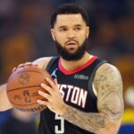 Fred VanVleet holding a basketball while wearing a black Houston Rockets jersey on the court