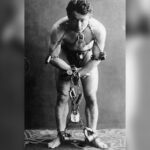 Historic portrait of Harry Houdini restrained in heavy chains and padlocks