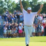 Golfer Henrik Stenson raises his arms in celebration in front of a cheering crowd at a tournament