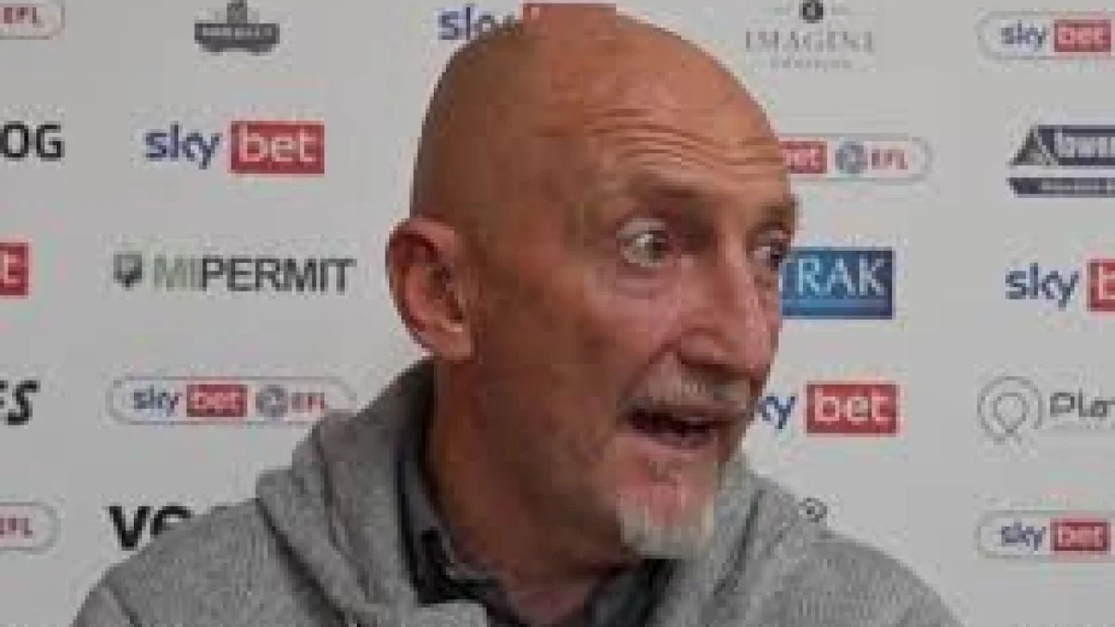 Swindon Town manager Ian Holloway speaking during a press interview in front of a sponsor backdrop