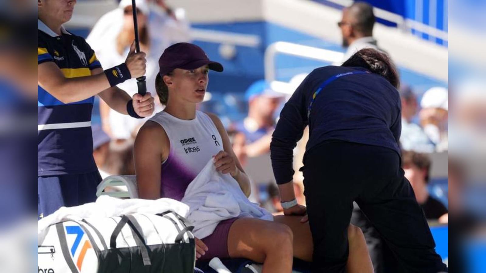 Tennis player Iga Swiatek sitting courtside holding a white towel during a match at the US Open