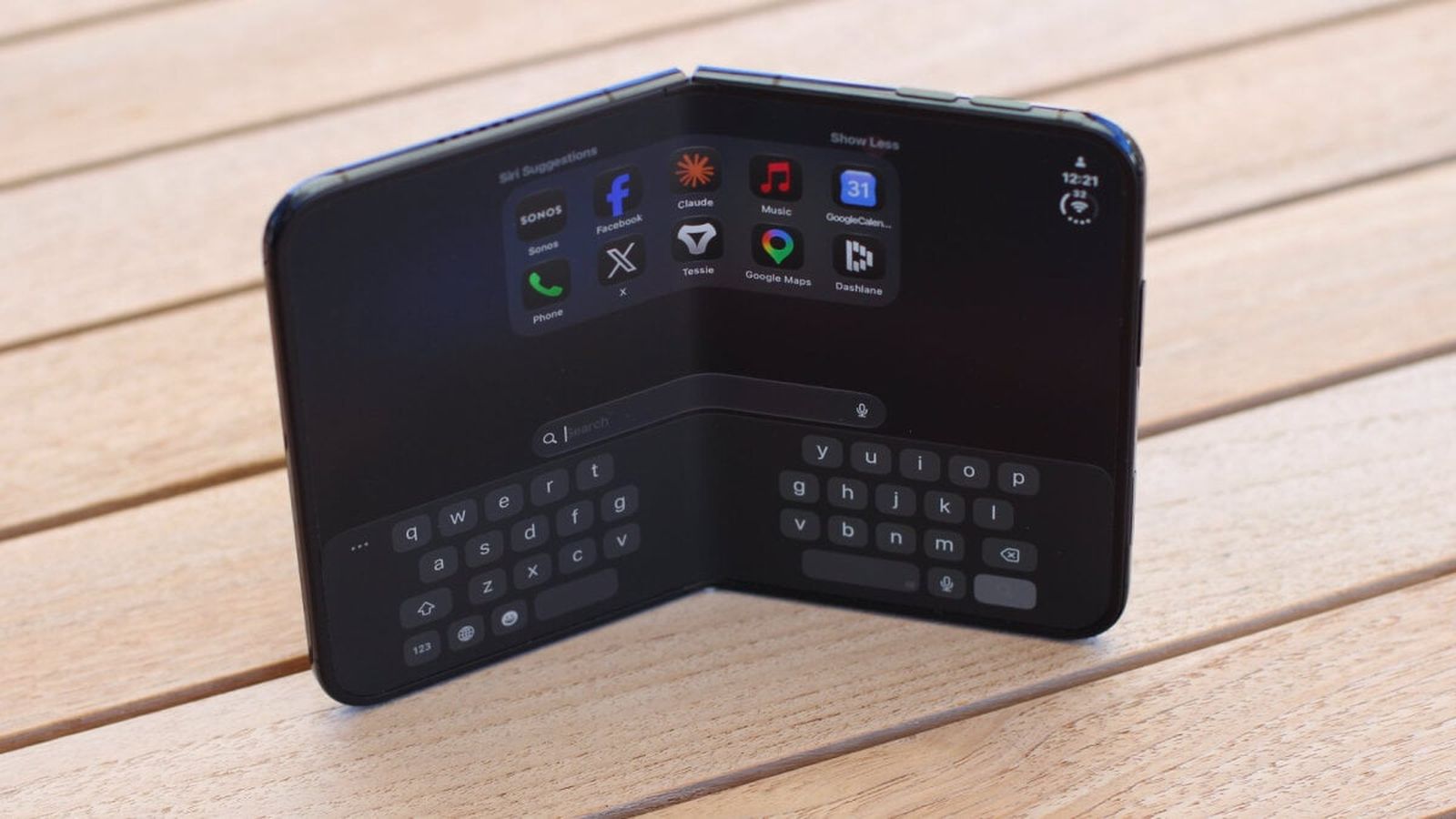 A close-up of a black foldable smartphone resting open on a wooden surface