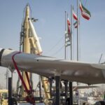 Iranian military hardware including a white drone and ballistic missiles on display outdoors