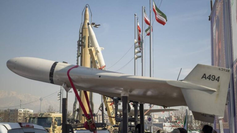 Iranian military hardware including a white drone and ballistic missiles on display outdoors