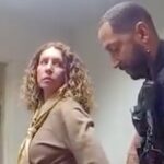 A woman with curly hair is detained by an Orlando police officer indoors