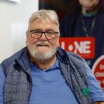 An older man with glasses and a beard smiling for the camera