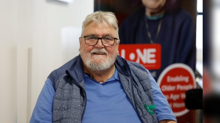 An older man with glasses and a beard smiling for the camera