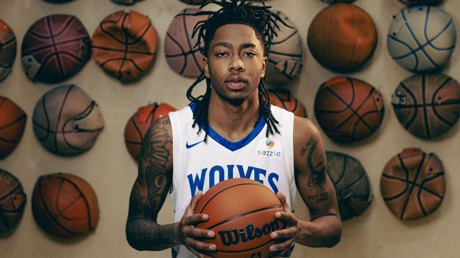Basketball player Isaiah Evans wearing a Minnesota Timberwolves jersey holds a basketball against a