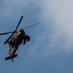 An Israeli military helicopter flies against a clear blue sky during operations