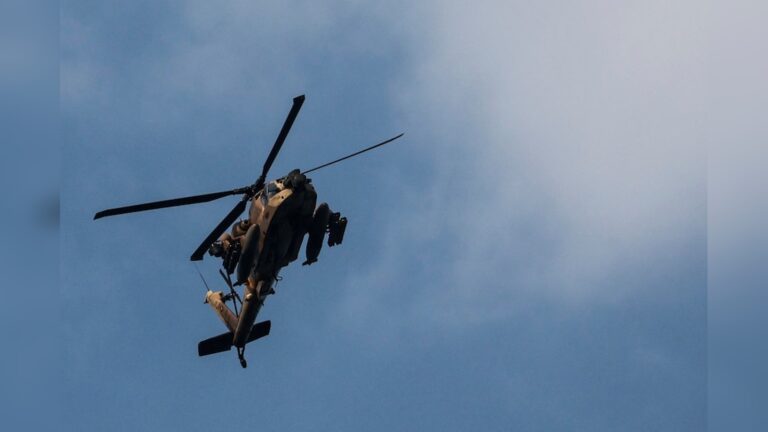 An Israeli military helicopter flies against a clear blue sky during operations