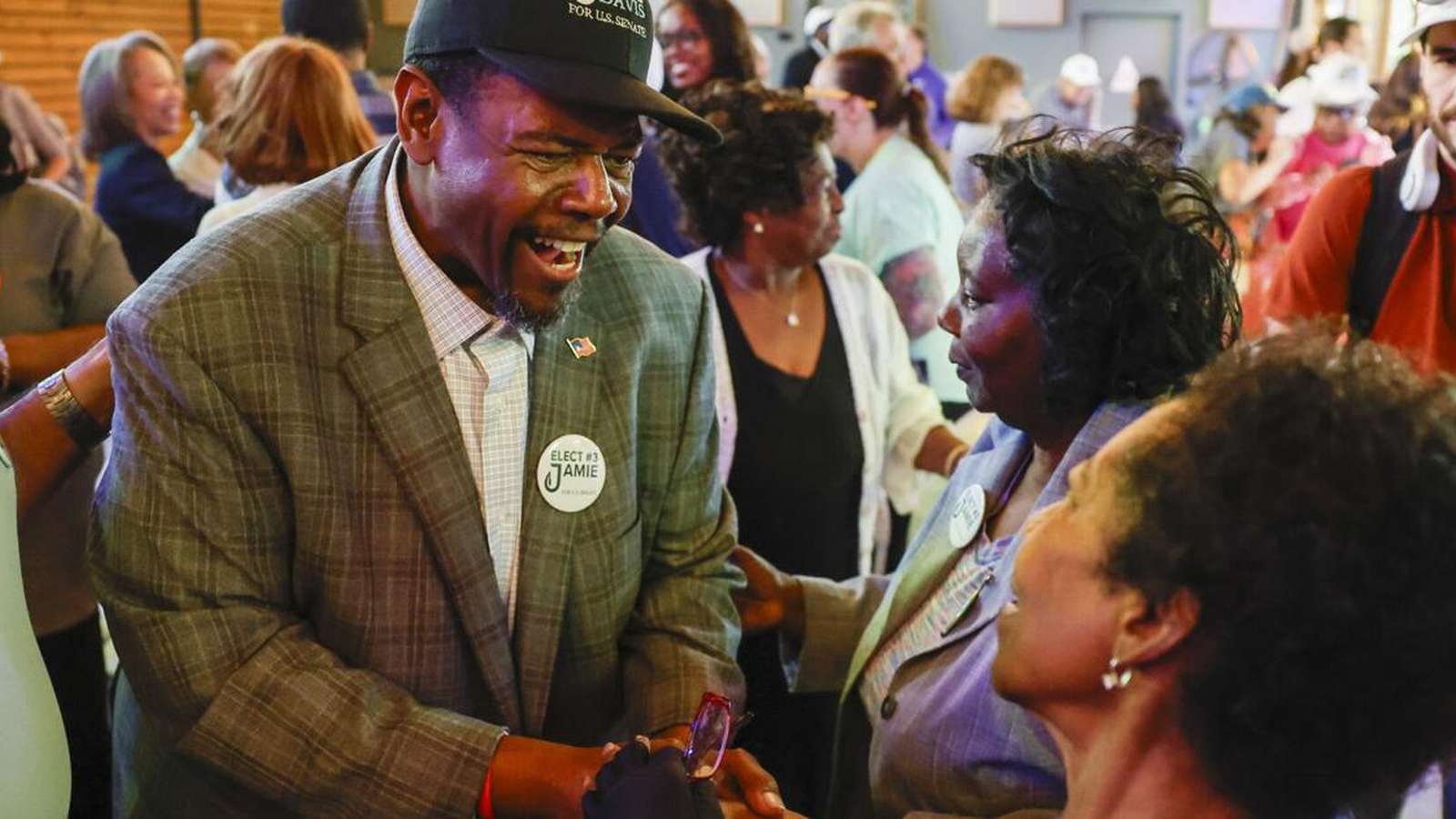 Senate candidate Jamie Davis smiling and shaking hands with supporters during a campaign event