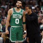 Jayson Tatum wearing Boston Celtics green jersey listening to coach during game
