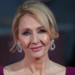 Close-up portrait of author J.K. Rowling wearing dangling earrings and a dark pink dress