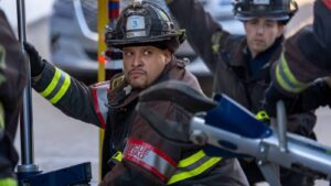 Actor Joe Minoso wearing a firefighter helmet and gear on Chicago Fire set