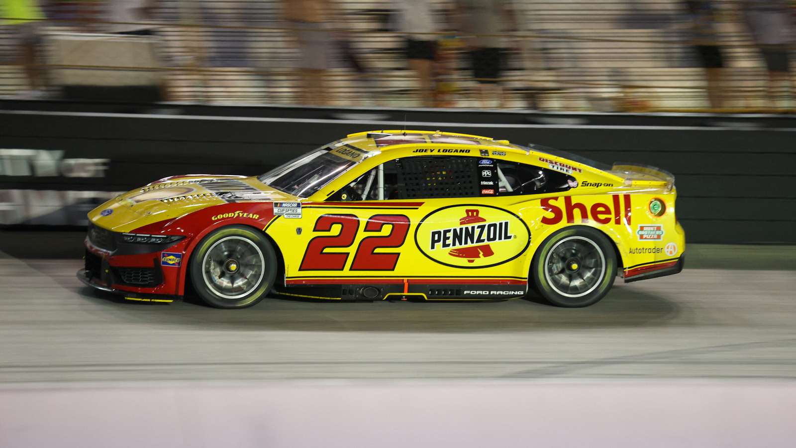 Joey Logano driving his yellow and red number 22 Shell Pennzoil Ford Mustang on the racetrack