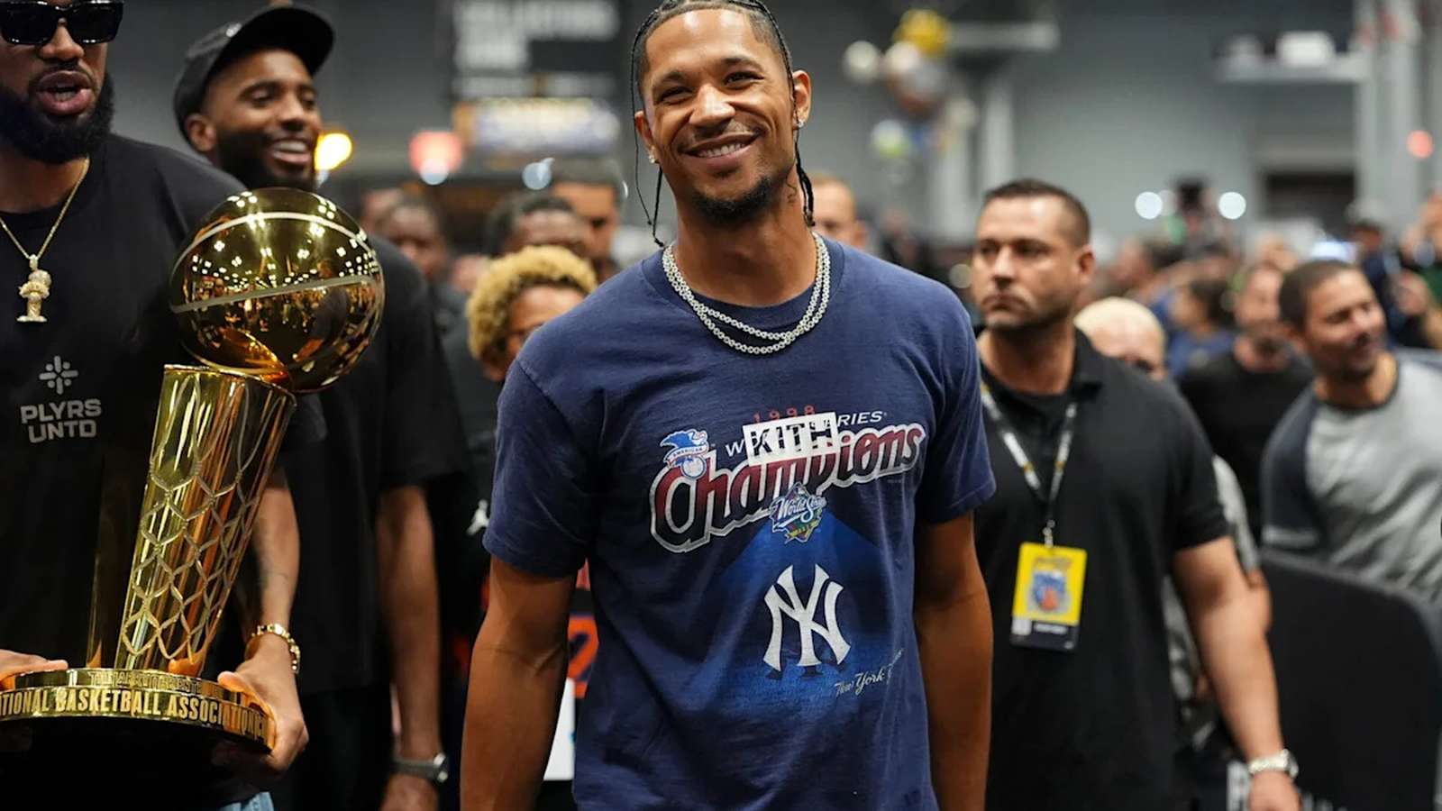 Josh Hart smiling while wearing a championship t-shirt with teammates surrounding him
