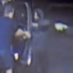 Grainy surveillance camera footage showing people during an armed robbery incident outdoors at night