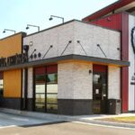Exterior view of a modern KFC restaurant building with drive-thru and Colonel Sanders logo