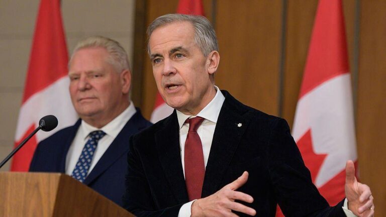 Prime Minister Mark Carney speaking at a podium with Canadian flags in the background