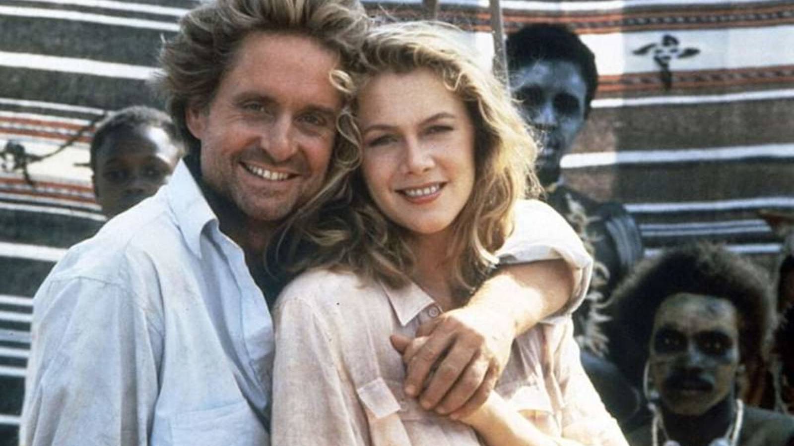 Actors Michael Douglas and Kathleen Turner smiling together outdoors on a film set
