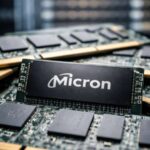 Close-up view of a Micron memory module resting on computer circuit boards with server racks in the