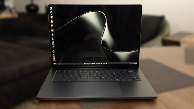 A dark modern laptop displaying an abstract wallpaper on its bright screen