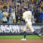 A Milwaukee Brewers baseball player running past cheering fans in the stands during a game