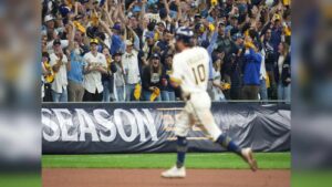 A Milwaukee Brewers baseball player running past cheering fans in the stands during a game