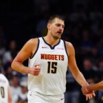 Nikola Jokic wearing a white Denver Nuggets jersey with number 15 on the court