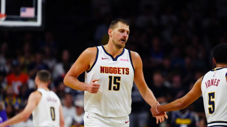 Nikola Jokic wearing a white Denver Nuggets jersey with number 15 on the court