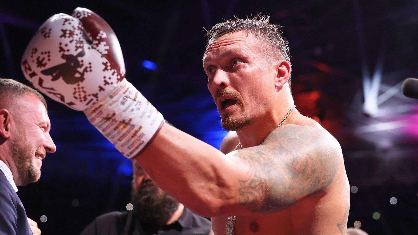 Heavyweight boxer Oleksandr Usyk raising his gloved hand inside the ring