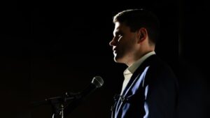 Profile view of a man in a suit speaking into a microphone